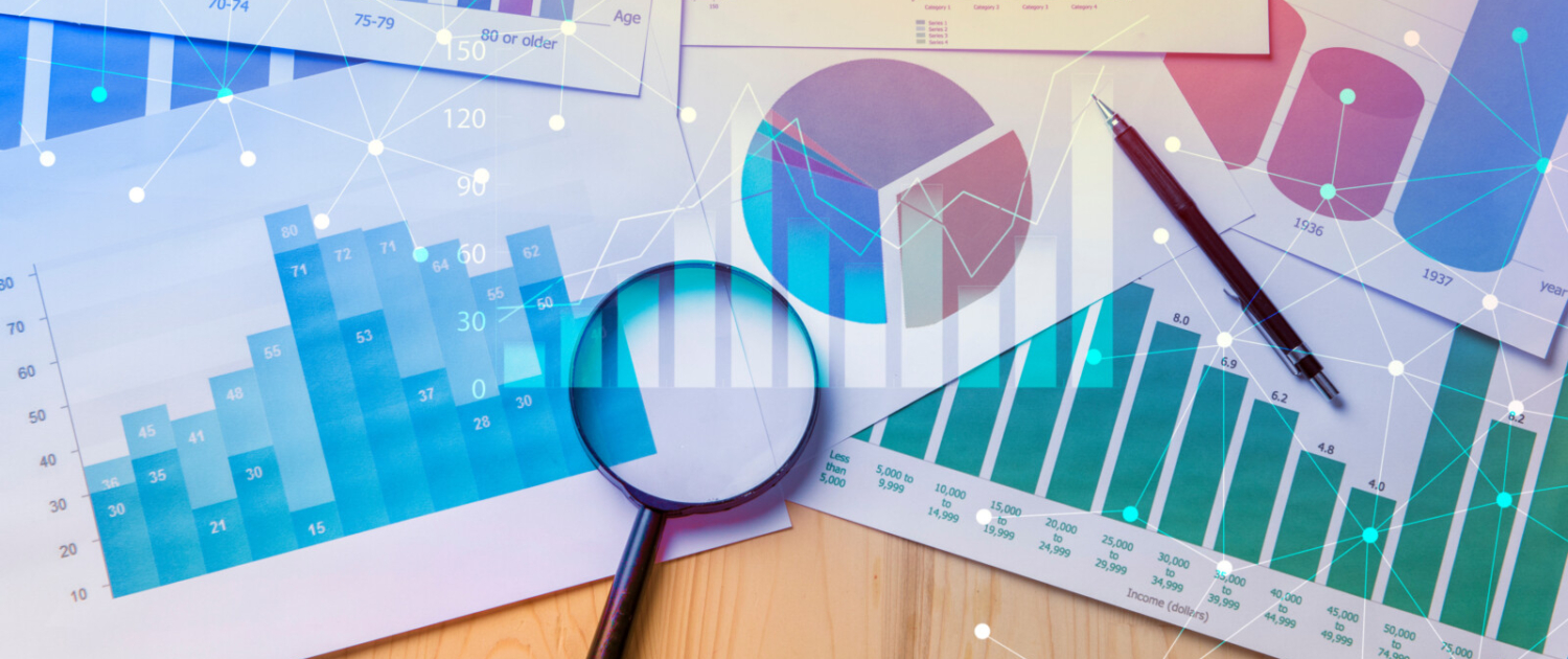 Magnifying glass and documents with analytics data lying on tabl